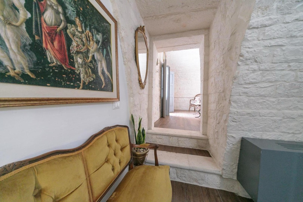 Divano giallo sotto un grande dipinto, in un passaggio della casa