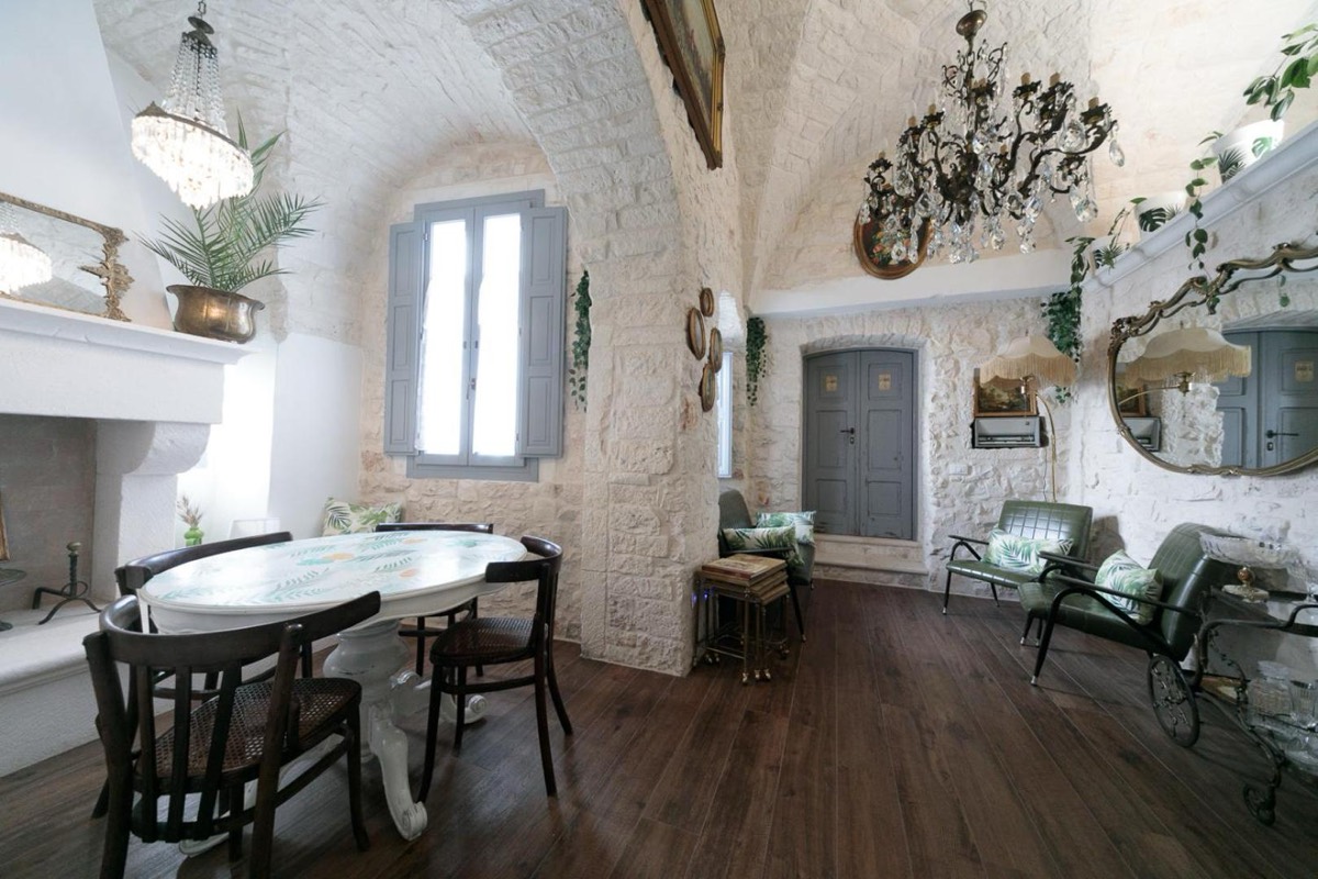 Sala da pranzo con tavolo ovale in marmo sotto una volta a stella, specchi e sedie d'epoca