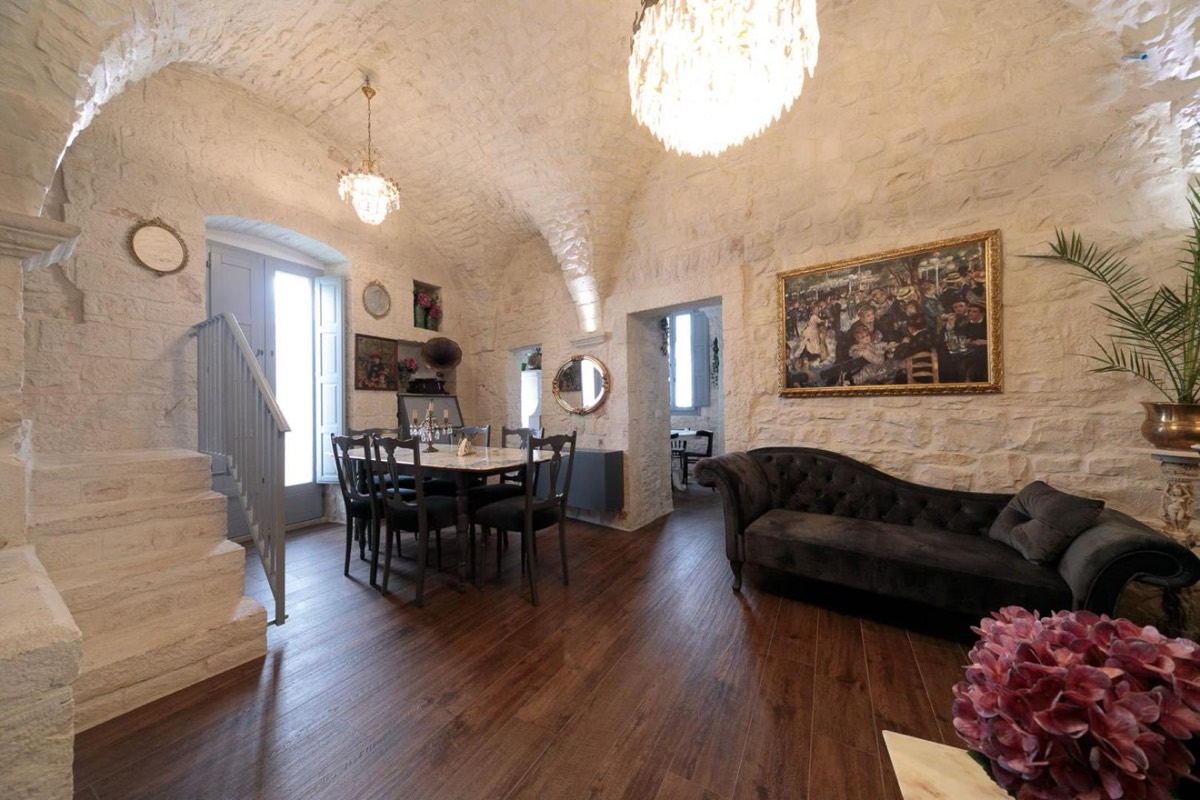 Sala comune con divani in pelle, quadri e la volta in pietra imbiancata