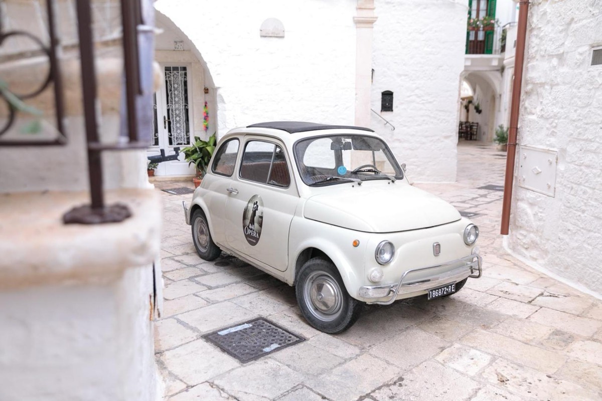 Una Fiat 500 bianca parcheggiata in una corte imbiancata a calce del centro storico di Locorotondo